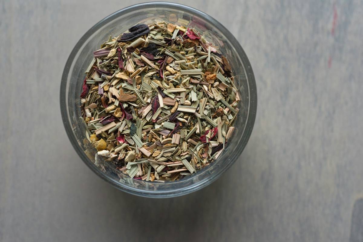 Woman preparing Immune Support herbal tea with organic tulsi and ginger in kitchen